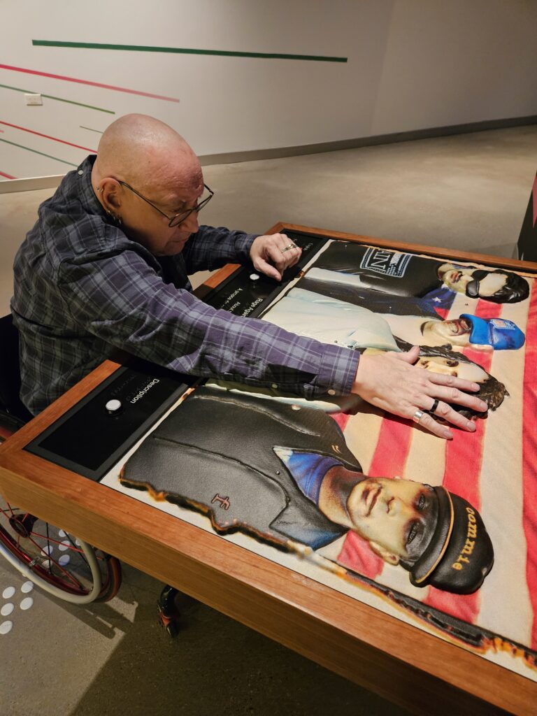 Peter a bald man in a wheelchair is using an interactive Museum display
