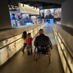 Peter rolling his wheelchair down a ramp with two children