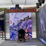 Peter in his wheelchair in front of a large video display